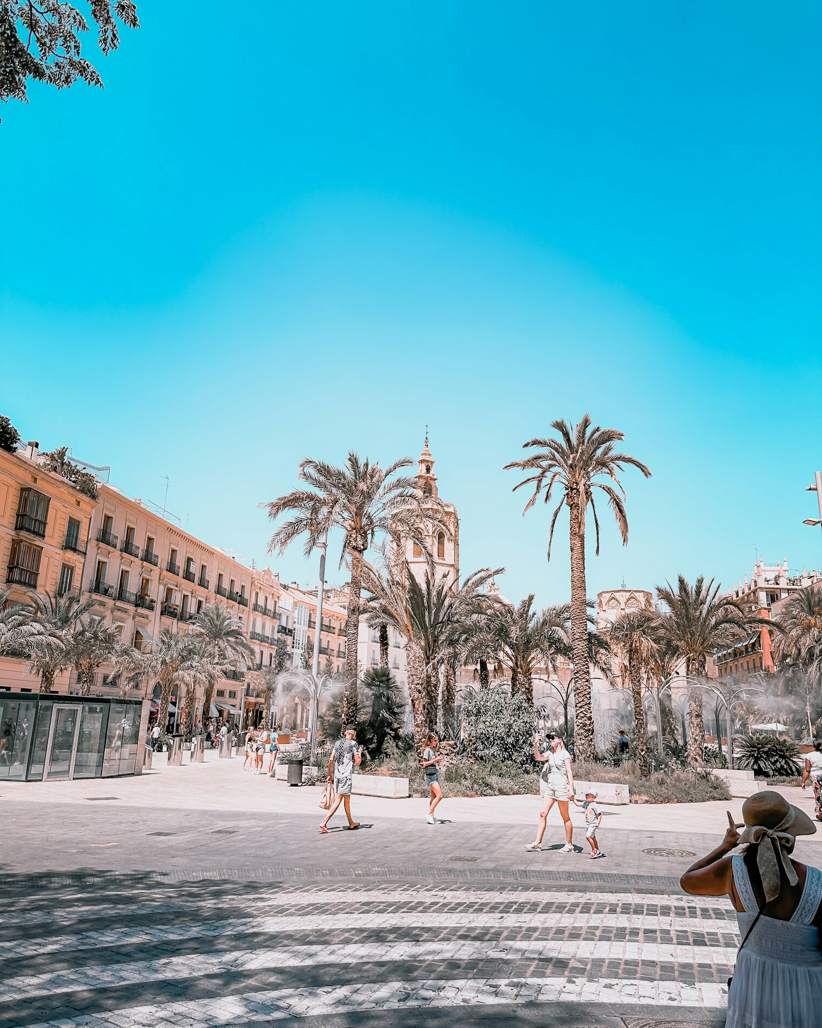 Family walking through a sunny Spanish plaza with palm trees